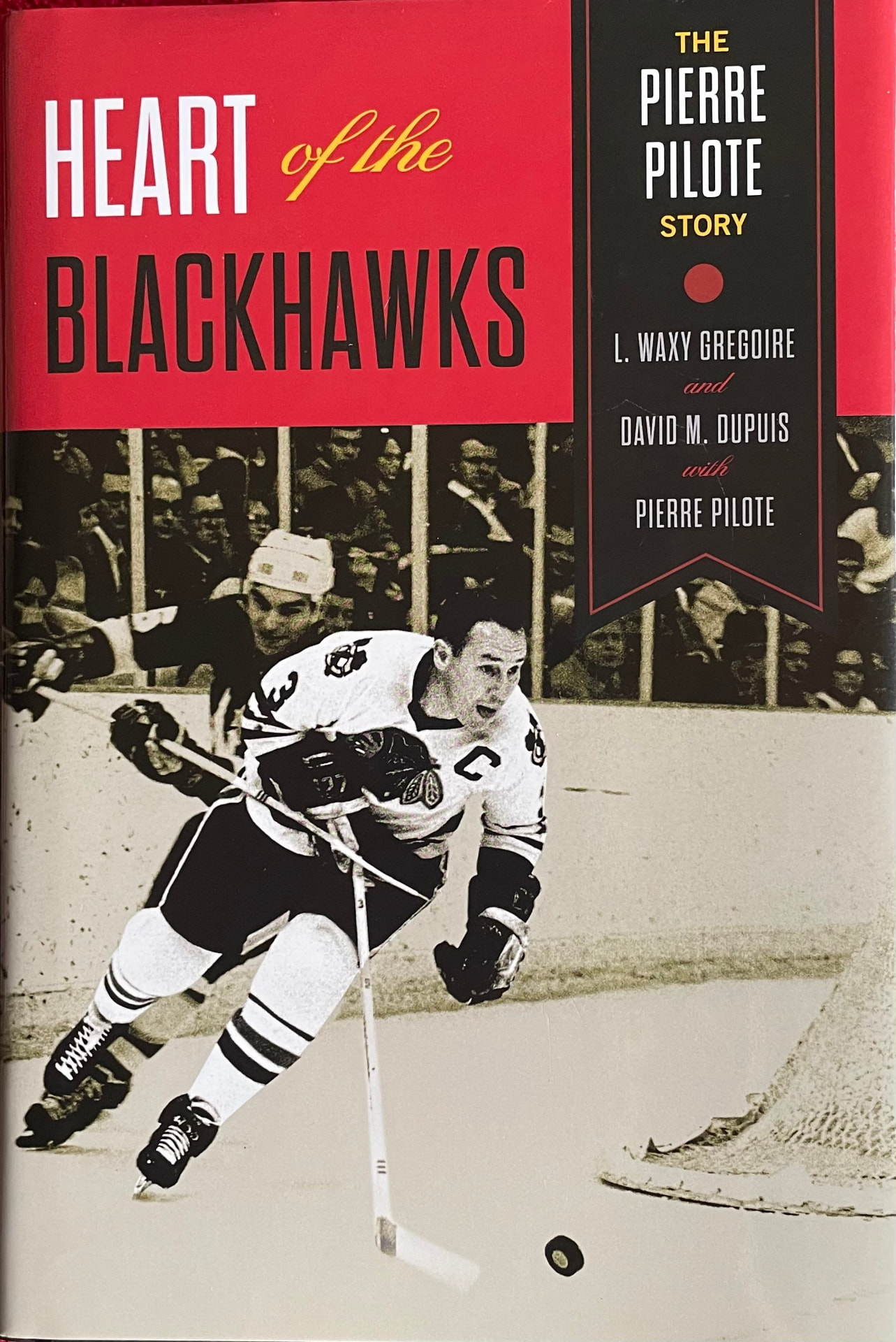Cover of Heart of the Blackhawks: The Pierre Pilote Story by L. Waxy Gregoire and David M. Dupuis, with Pierre Pilote — a red title band above a black-and-white photograph of Pilote skating with the puck